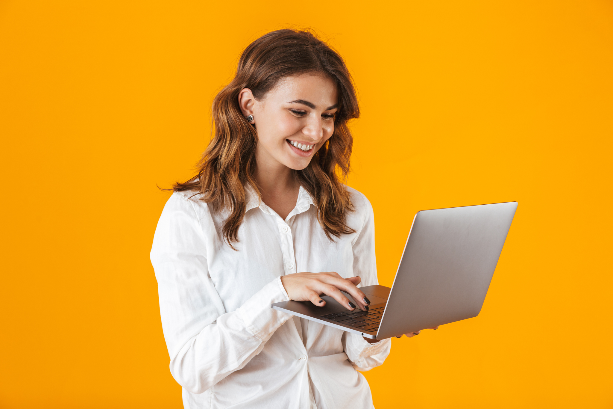 Portrait of a cheerful young woman wearing white shirt holding laptop